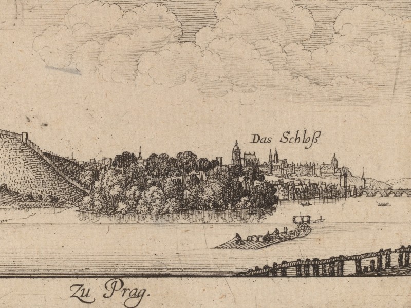 Prague viewed from a distance, with the Vltava River in the foreground and Prague Castle far away in the back.